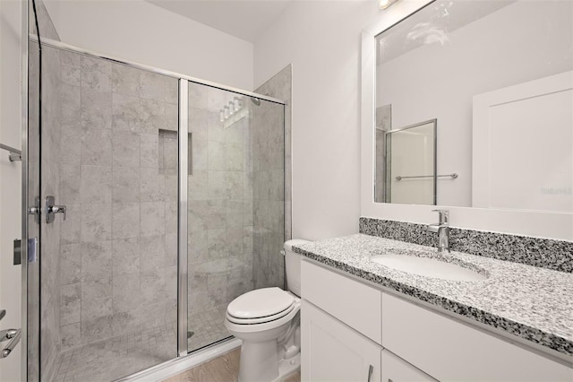 bathroom with vanity, wood-type flooring, a shower with shower door, and toilet