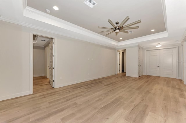 interior space with crown molding, ceiling fan, a raised ceiling, and light hardwood / wood-style floors