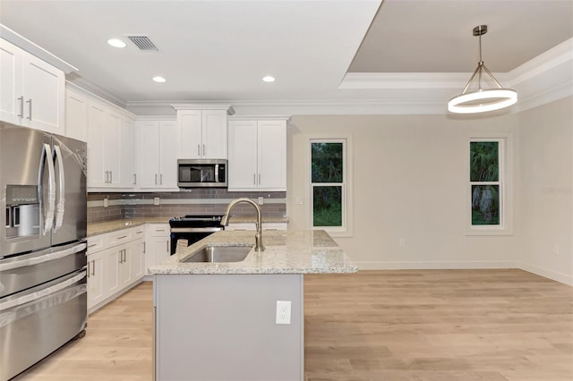 kitchen featuring pendant lighting, sink, appliances with stainless steel finishes, white cabinets, and a center island with sink