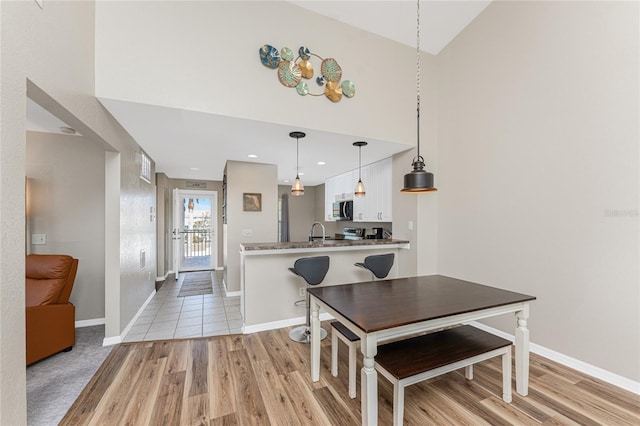 dining room with a high ceiling, sink, and light wood-type flooring