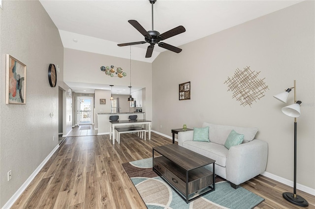 living room with hardwood / wood-style flooring, ceiling fan, and high vaulted ceiling