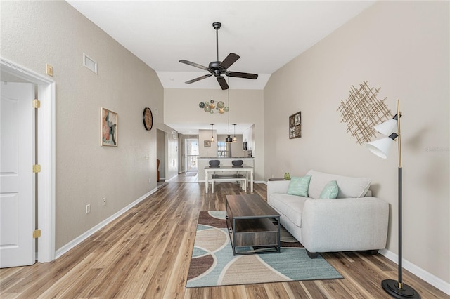 living room featuring hardwood / wood-style flooring, vaulted ceiling, and ceiling fan