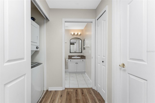 interior space with stacked washing maching and dryer, light hardwood / wood-style floors, and sink