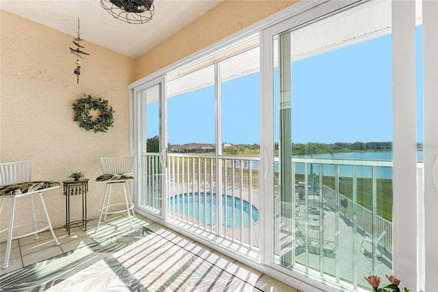 sunroom featuring a water view