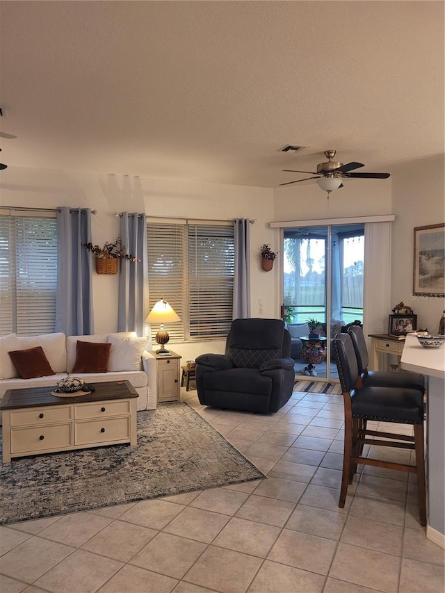 tiled living room with ceiling fan and a textured ceiling