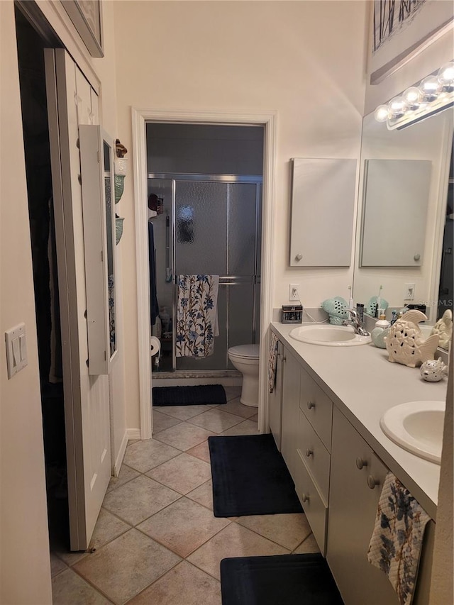 bathroom featuring tile patterned flooring, toilet, vanity, and walk in shower