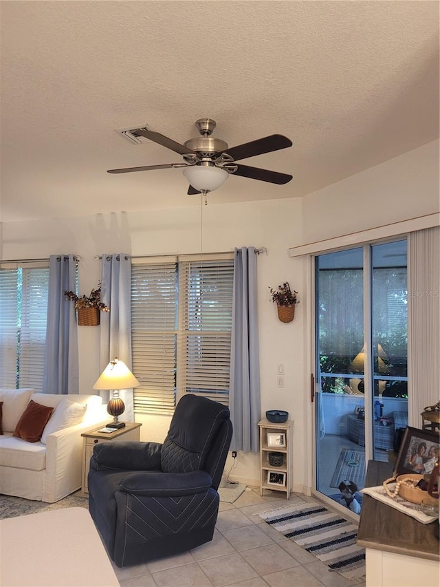 tiled living room with ceiling fan and a textured ceiling