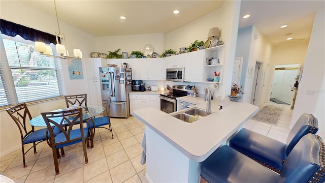 kitchen featuring sink, hanging light fixtures, appliances with stainless steel finishes, kitchen peninsula, and white cabinets