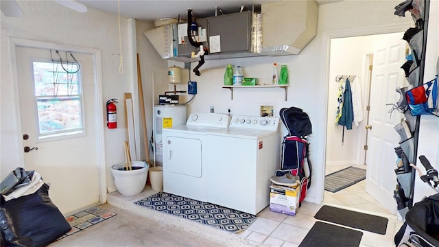 clothes washing area featuring light tile patterned floors, water heater, and washing machine and clothes dryer