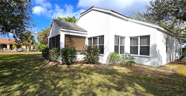 view of home's exterior with a lawn and a sunroom