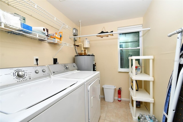 clothes washing area with independent washer and dryer, light tile patterned floors, and water heater