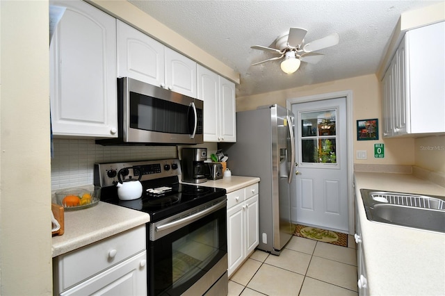 kitchen with stainless steel appliances, white cabinetry, light tile patterned floors, and a textured ceiling