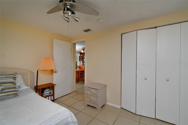 tiled bedroom with a textured ceiling and ceiling fan