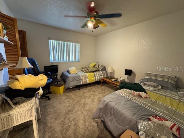 bedroom featuring light carpet, a textured ceiling, and ceiling fan