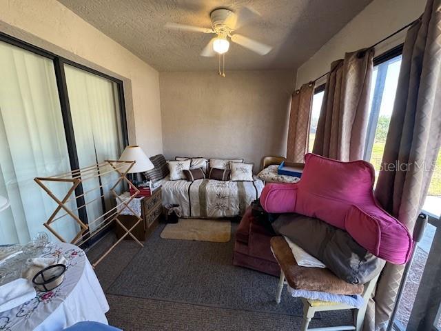 bedroom featuring ceiling fan, carpet floors, and a textured ceiling