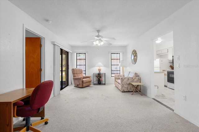 living area with light carpet, ceiling fan, and a textured ceiling