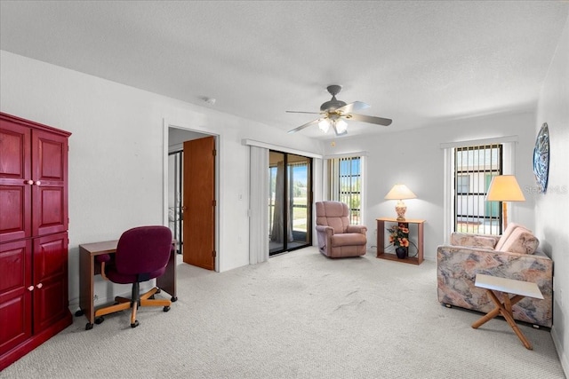 sitting room with light carpet, ceiling fan, and a textured ceiling