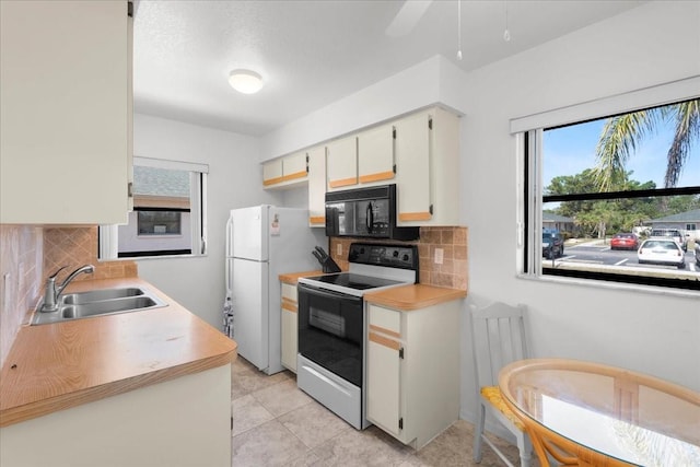 kitchen with white appliances, decorative backsplash, light countertops, white cabinetry, and a sink