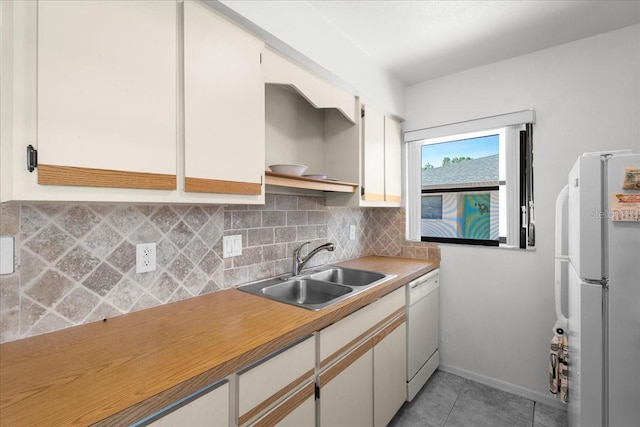 kitchen with tasteful backsplash, white cabinetry, a sink, light tile patterned flooring, and white appliances