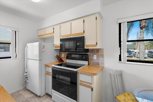 kitchen featuring light countertops, backsplash, electric range oven, freestanding refrigerator, and black microwave