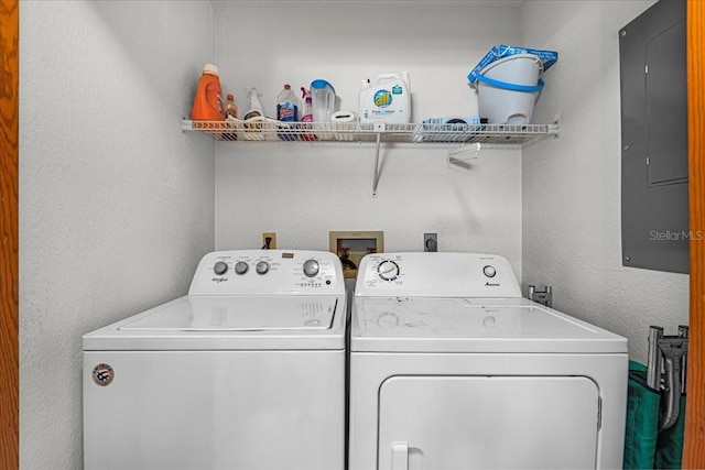 laundry room with a textured wall, laundry area, washing machine and clothes dryer, and electric panel