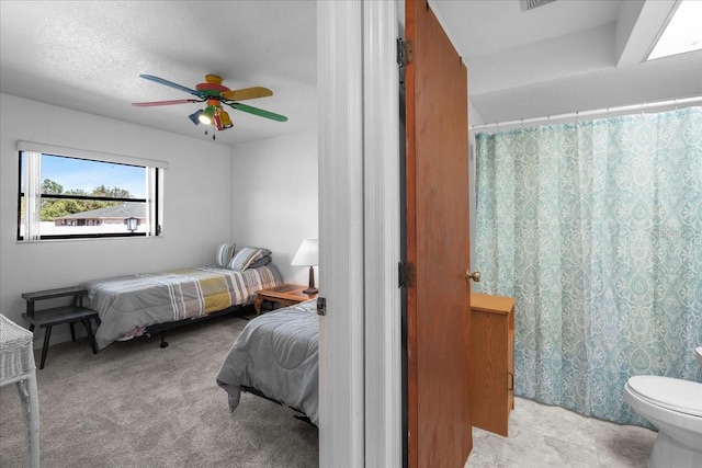 bedroom featuring light carpet, a textured ceiling, and a ceiling fan