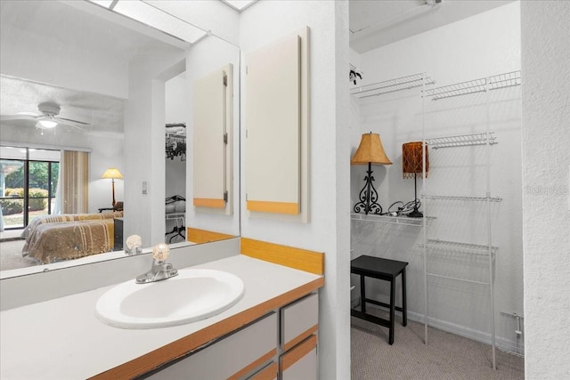 bathroom featuring ensuite bathroom, ceiling fan, a textured wall, and vanity