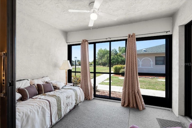 bedroom featuring a textured ceiling, a textured wall, a ceiling fan, and access to exterior