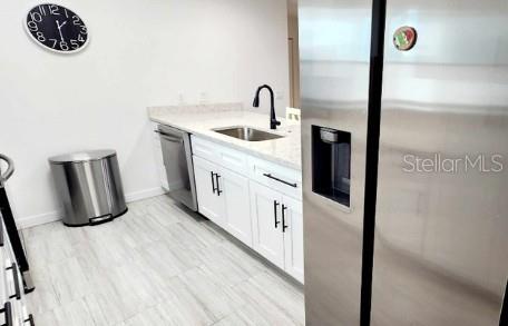 kitchen featuring white cabinetry, appliances with stainless steel finishes, sink, and light stone counters