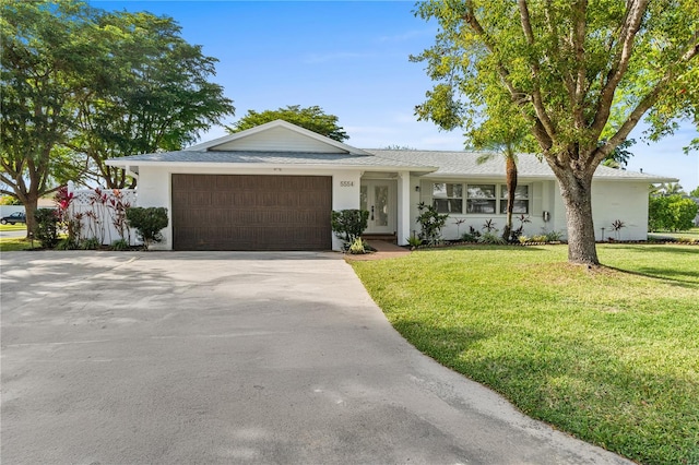 ranch-style home featuring driveway, a front lawn, an attached garage, and stucco siding