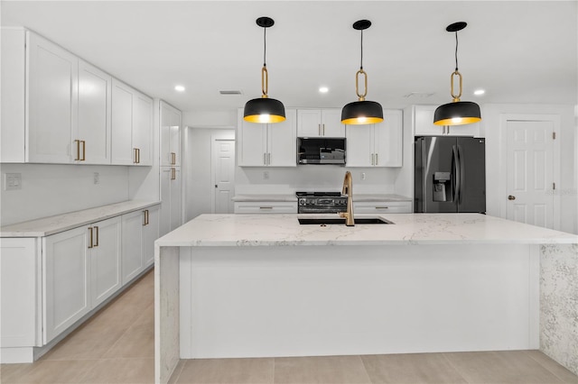 kitchen with stainless steel appliances, white cabinetry, and a center island with sink