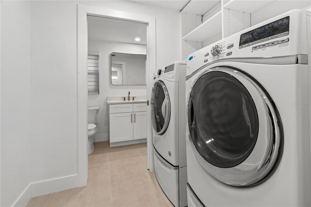 washroom with light tile patterned floors, laundry area, a sink, baseboards, and washer and clothes dryer