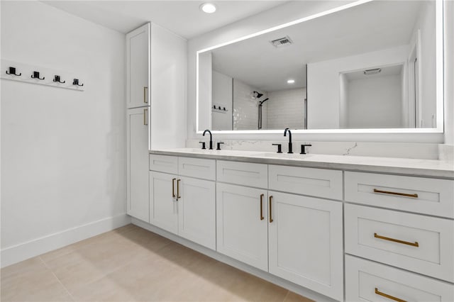 full bath featuring double vanity, baseboards, visible vents, and a sink