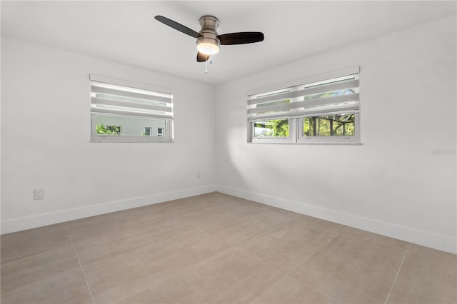 spare room with ceiling fan, baseboards, and light tile patterned floors