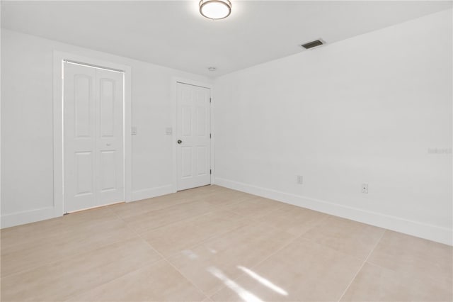 empty room with baseboards, visible vents, and light tile patterned flooring