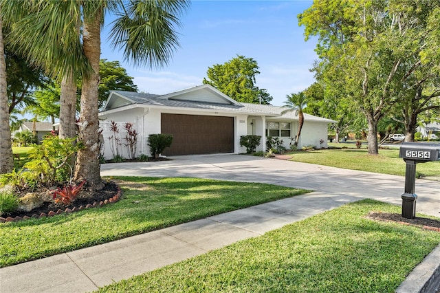 ranch-style home with a garage, concrete driveway, a front lawn, and stucco siding