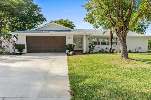 ranch-style home with an attached garage, concrete driveway, french doors, stucco siding, and a front lawn