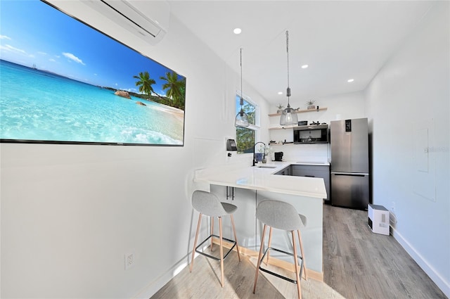 kitchen with appliances with stainless steel finishes, pendant lighting, sink, a kitchen bar, and kitchen peninsula