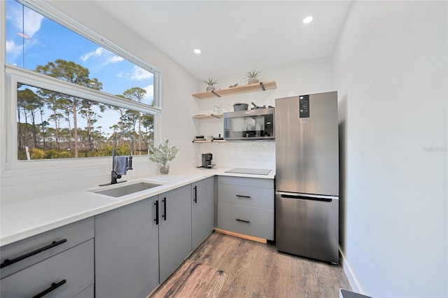 kitchen with stainless steel refrigerator, tasteful backsplash, sink, gray cabinetry, and light wood-type flooring