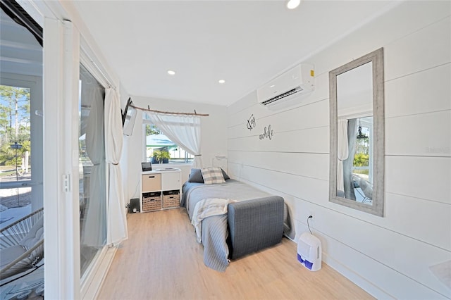 bedroom featuring light hardwood / wood-style flooring, a wall unit AC, and wooden walls