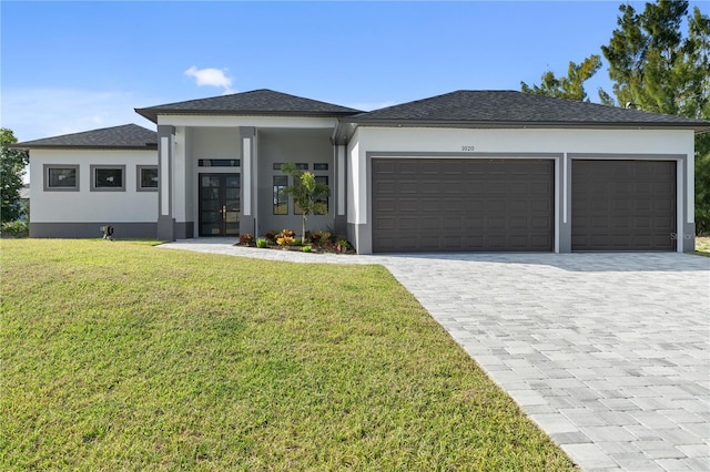 prairie-style home featuring a garage, a front lawn, decorative driveway, and stucco siding