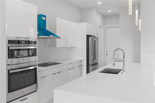 kitchen featuring modern cabinets, light stone countertops, range hood, stainless steel appliances, and a sink