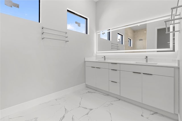 bathroom featuring a tile shower, marble finish floor, a sink, and baseboards