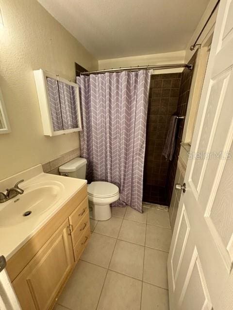 bathroom with vanity, toilet, tile patterned floors, and walk in shower