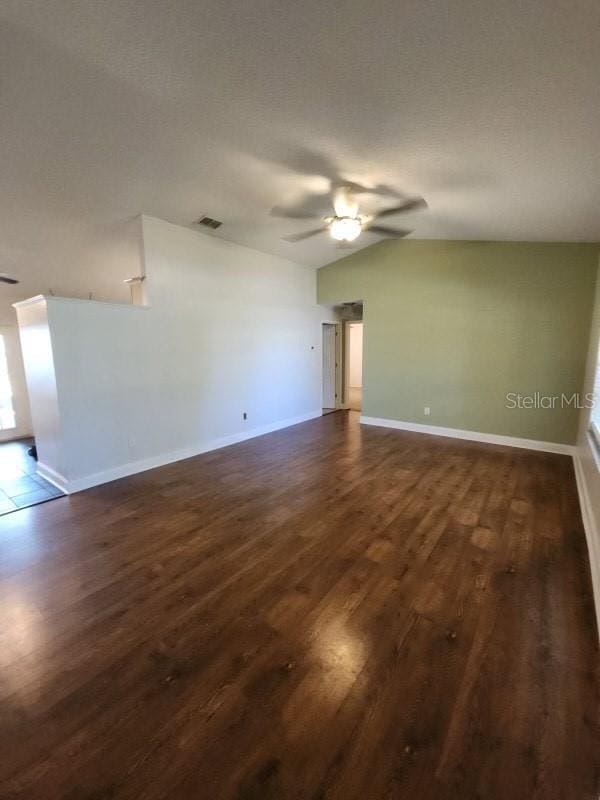 unfurnished room with visible vents, a ceiling fan, and dark wood-style floors