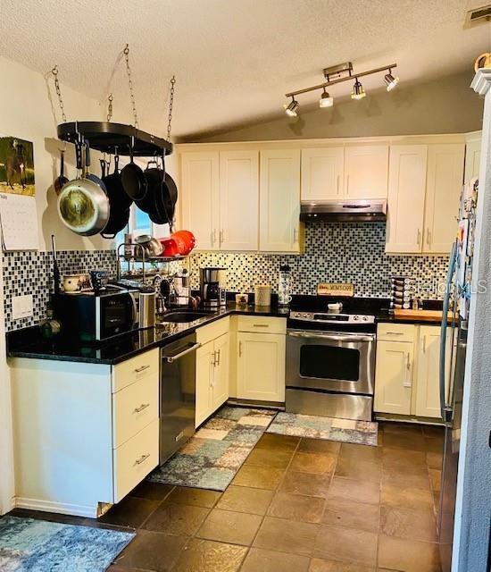 18085 Wintergarden Ave, Port Charlotte, FL 33948 - kitchen with stainless steel appliances, white cabinetry, tasteful backsplash, a textured ceiling, and under cabinet range hood