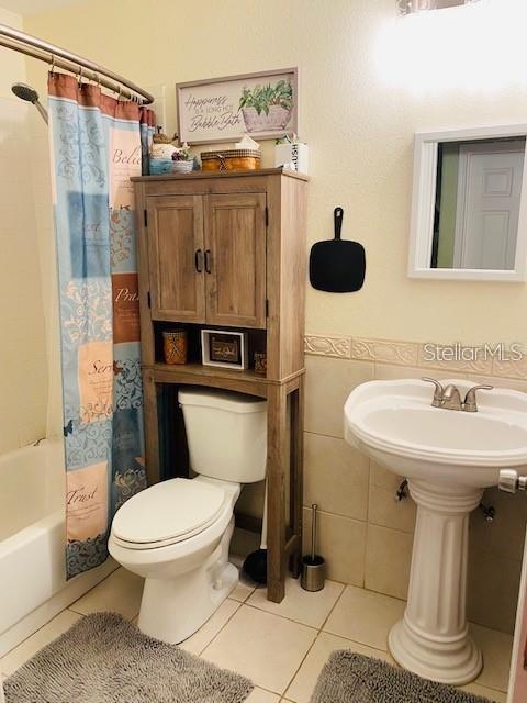 18085 Wintergarden Ave, Port Charlotte, FL 33948 - bathroom with tile patterned floors and shower / tub combo with curtain