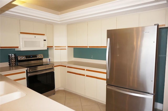 kitchen featuring stainless steel appliances, a raised ceiling, light tile patterned flooring, and white cabinetry