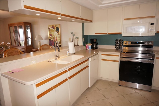 kitchen with sink, white cabinets, light tile patterned floors, kitchen peninsula, and white appliances