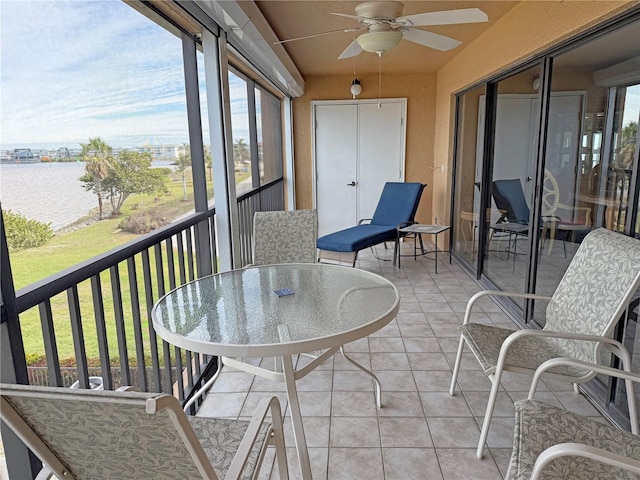 sunroom / solarium featuring ceiling fan and a water view